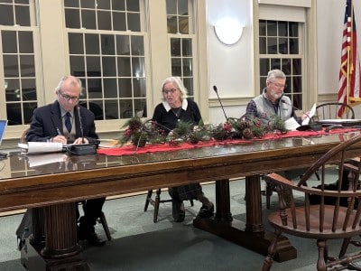 Members of the Board of Selectmen discuss issues from the long table at the front of the Town Hall meeting room.