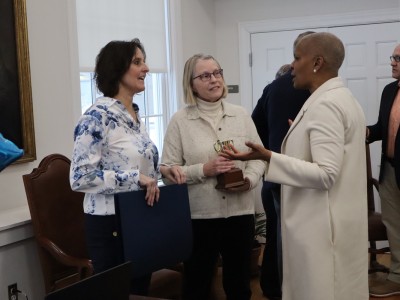 The three women speak while Thomas gestures with both hands.