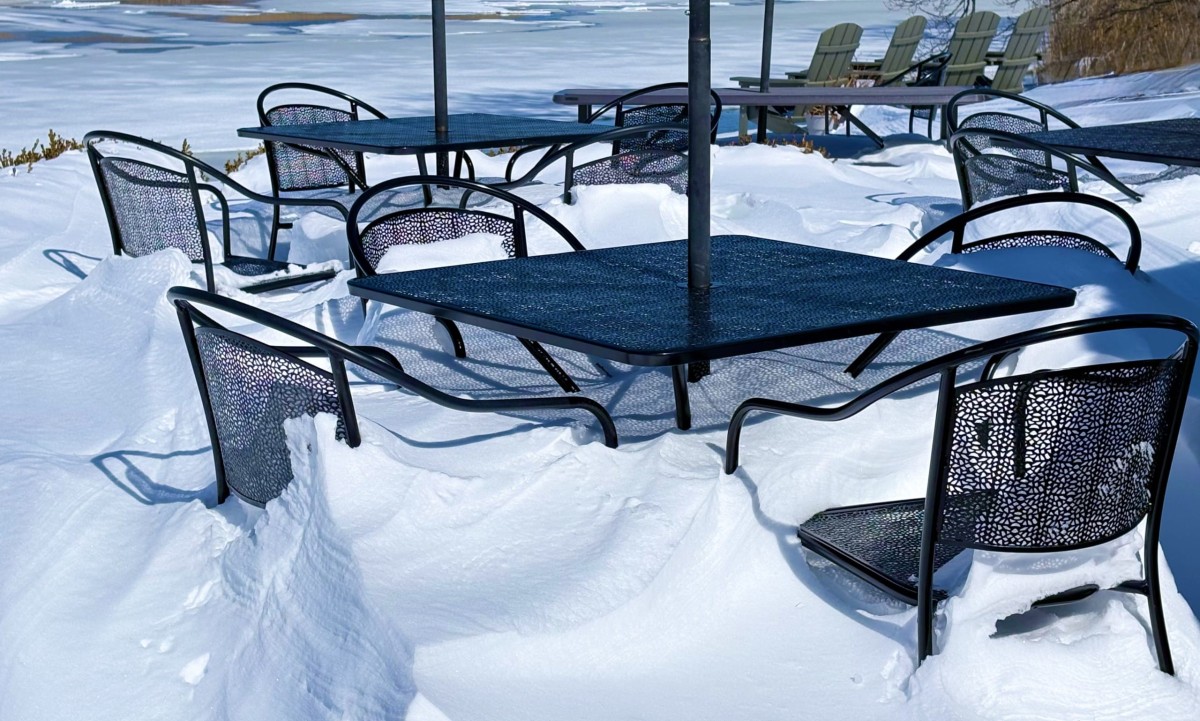 Tables and chairs used in warmer weather are buried to the seats in snow.
