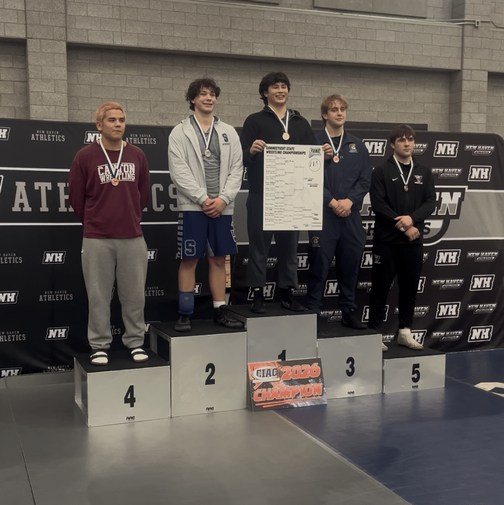 Gemme stands atop the podium holding a bracket poster in the middle of the top five finishers.