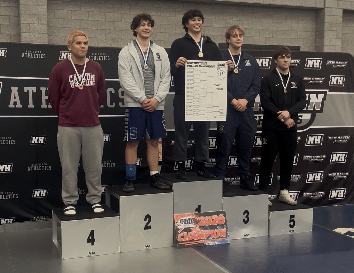 Gemme stands atop the podium holding a bracket poster in the middle of the top five finishers.