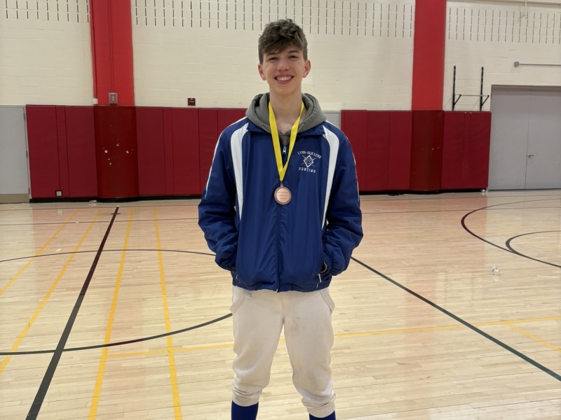 Cameron Russell poses while wearing his medal in a gymnasium.