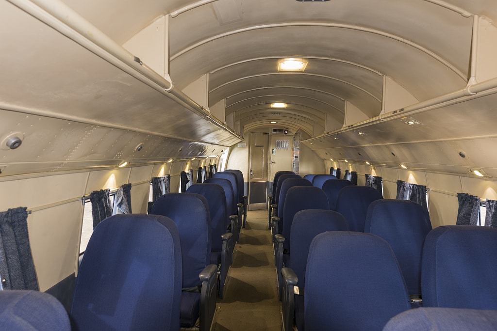 Blue seats, two to a row on one side and one per row on the other side, are shown in this interior shot of the plane.