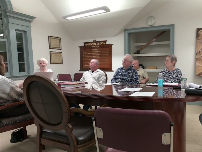 Members sit around an oval table almost as big as the room.