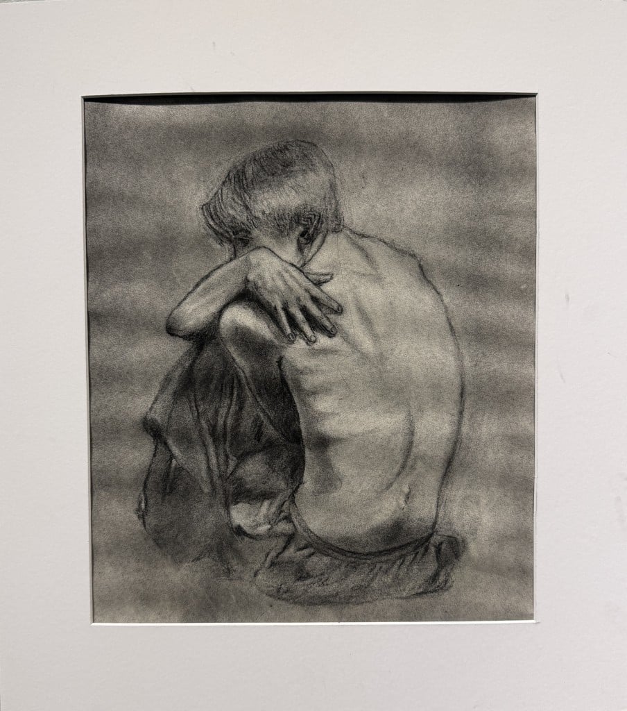 A shirtless young person sits hunched over.