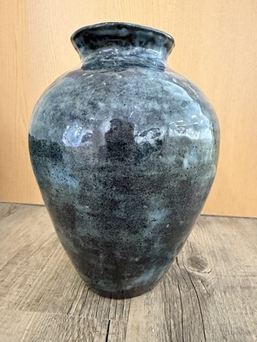 A vase in shades of turquoise, green and black. 