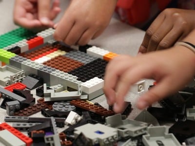 a pile of LEGOS with hands visible piecing them together.