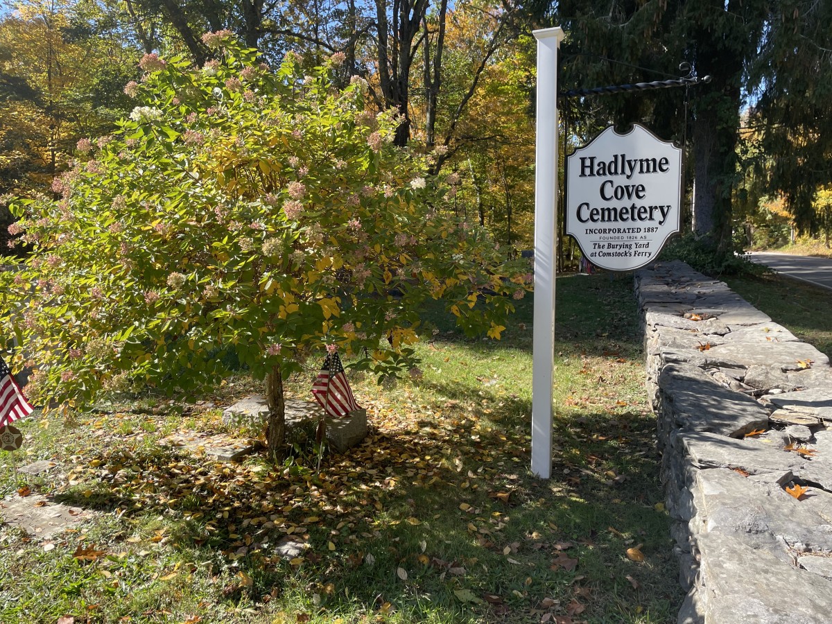 The Hadlyme Cove Cemetery sign is sceen in the shade of a tree.
