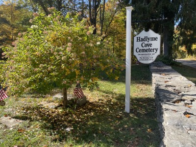 The Hadlyme Cove Cemetery sign is sceen in the shade of a tree.