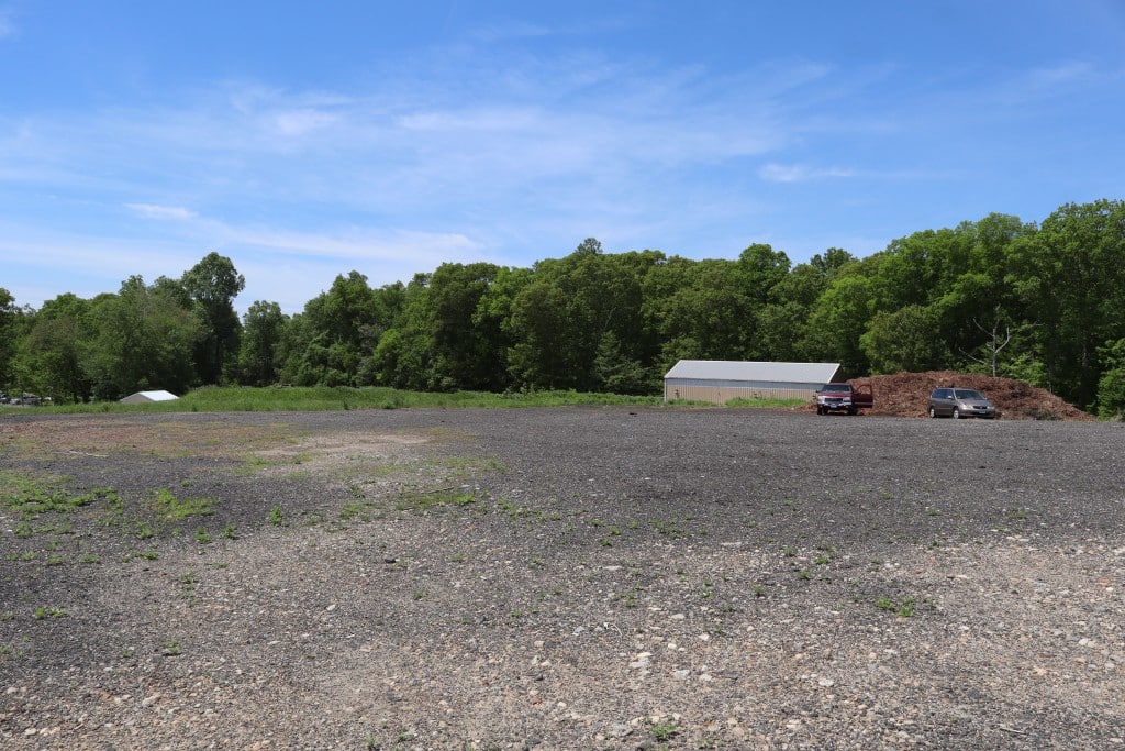 A flat gravel covered expanse with a large shed in the distance.