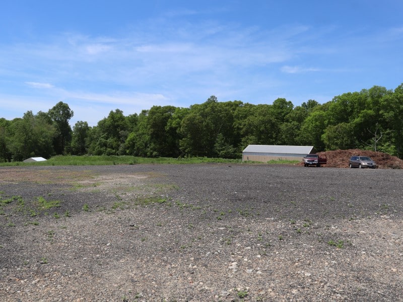 A flat gravel covered expanse with a large shed in the distance.