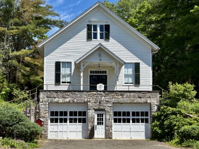 The front of the Lyme Public Hall surrounded by green trees and bushes.