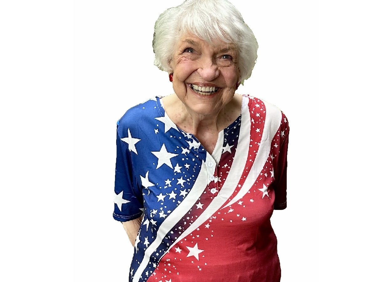 Woman with white hair in sparkly red, white and blue shirt.
