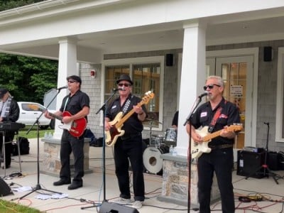 Four band members play outside the senior center side porch.