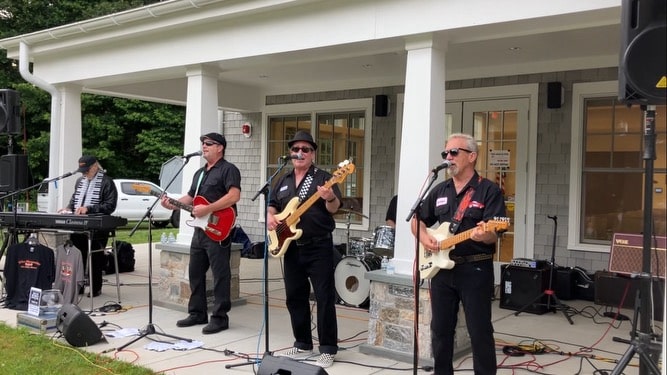 Four band members play outside the senior center side porch.