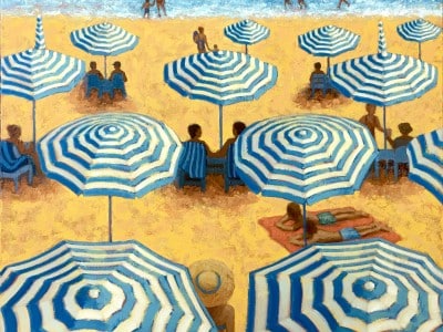 People sit under and around blue and white beach umbrellas on yellow-hued sand in front of blue water.