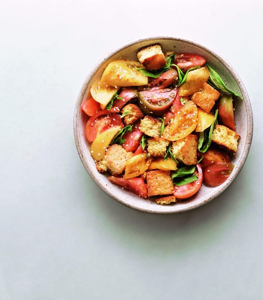 Tomato and crutons in a white bowl with herbs and sesame seeds