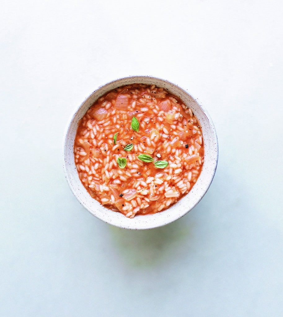 risotto and tomato sauce in a white bowl with a light backgroud